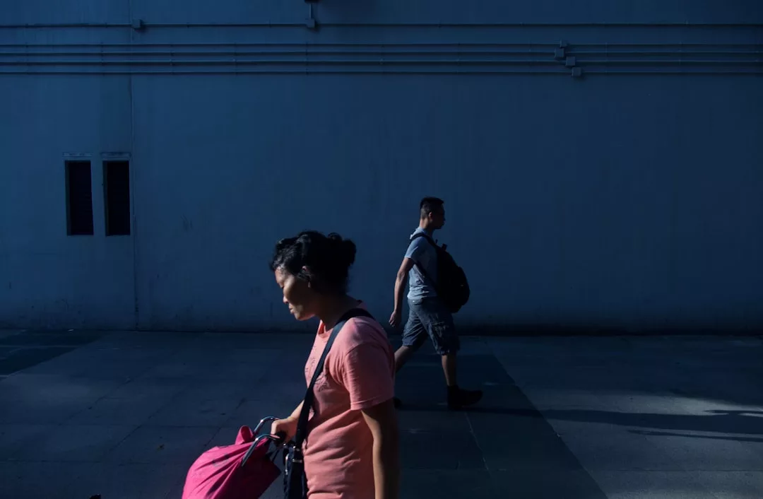 woman walking near man beside white wall at daytime